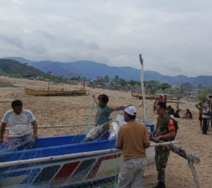 Babinsa Hu’u Bantu Nelayan Turunkan Perahu di Pantai Jala