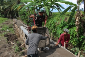 Babinsa Desa Batuan Hadir di Garis Depan Pembangunan Jalan TMMD