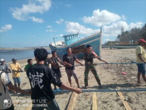 Babinsa Ikut Gotong Royong Bersama Warga Angkat Perahu Nelayan