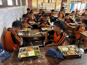 Dampingi Yayasan Bali Arta Pardana, Babinsa Pastikan Ribuan Pelajar di Sumberkima Terima Menu Sehat Berupa Burger dan Kelengkeng